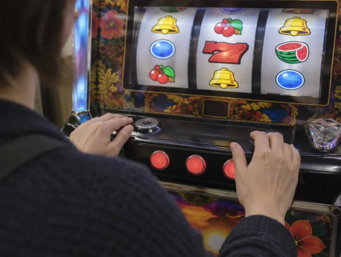 Hands at a pachislot panel showing how to play